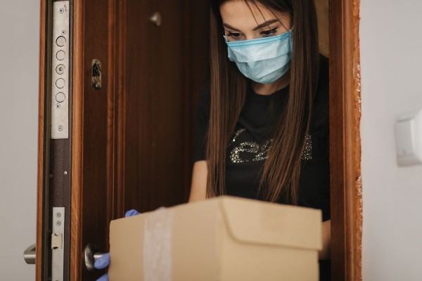 Una cliente recoge un paquete depositado en la puerta como precaución ante el coronavirus