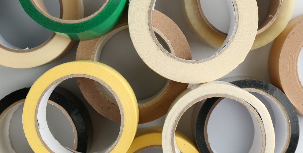 Rolls of different adhesive tapes on white background, flat lay